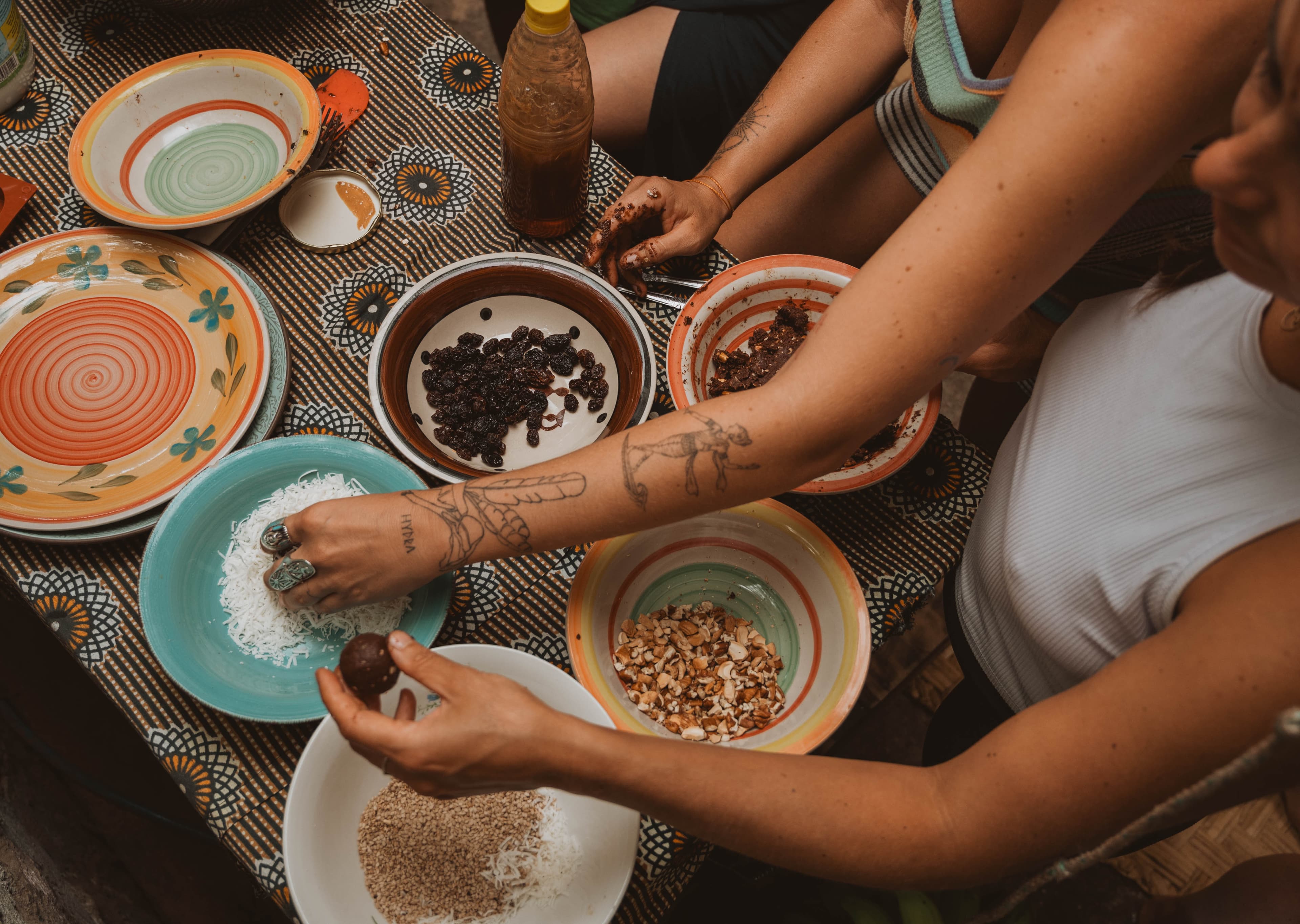Hands rolling cacao treats together at a communal table