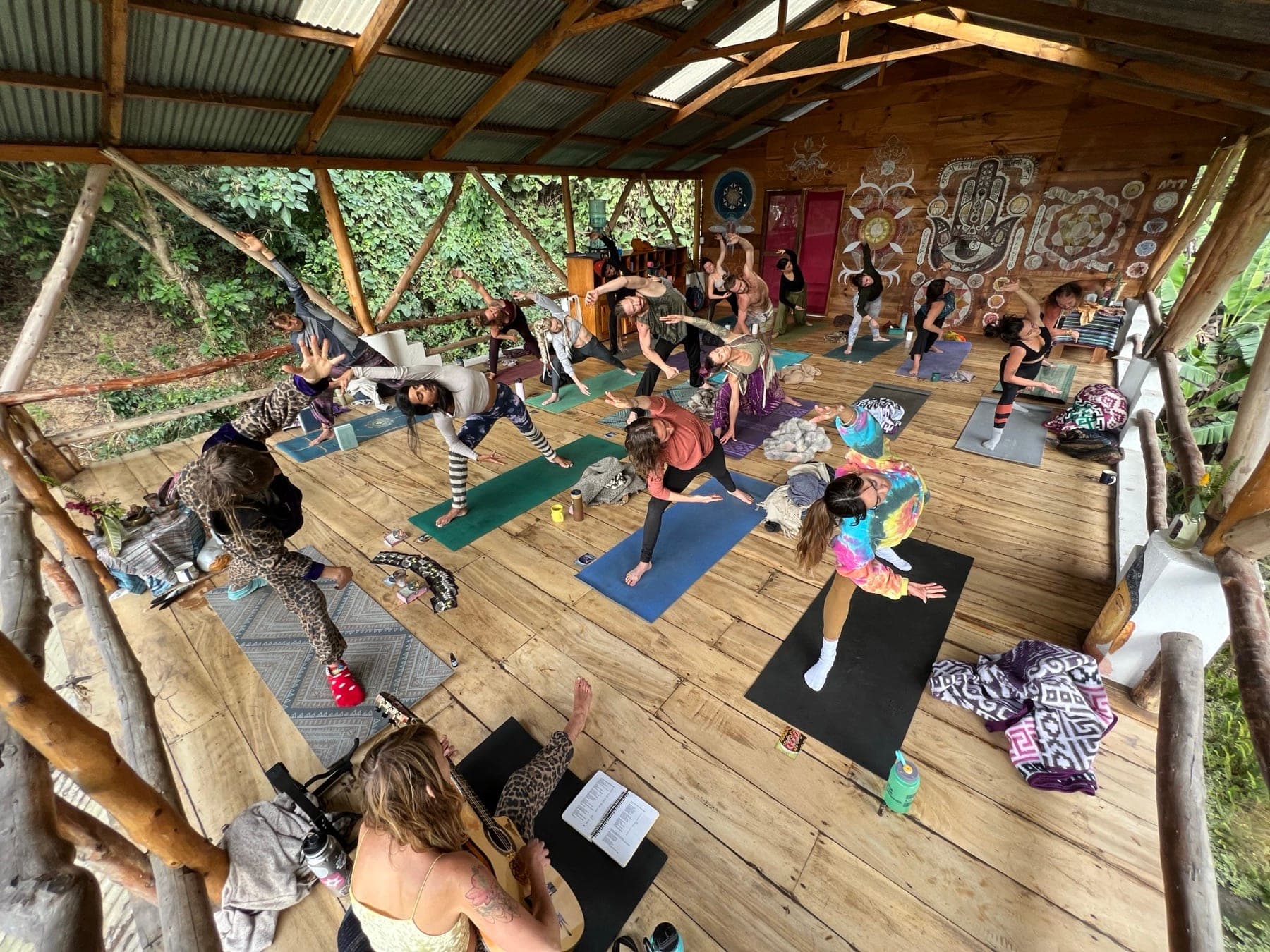 Yoga class in an open-air shala at Mystical Yoga Farm, with live guitar
